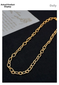 Detail shot of golden twisted rope link chain necklace on textured black fabric