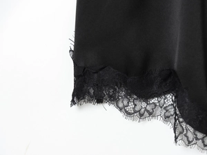 Dettaglio ravvicinato dell'orlo in raso nero con bordo in pizzo di un abito elegante