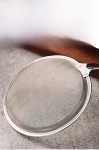 Macro detail of fine mesh stainless steel strainer showing mirror polished rim and net