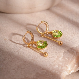 Detailed view of leaf-shaped gold drop earring with light green stone and green zircon crystals
