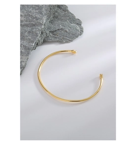 Macro shot of gold-plated silver cuff bracelet with cubic zirconia on gray rock