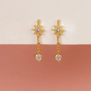 Detailed view of gold starburst earrings with clear zircon stones on a pedestal