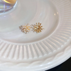 Vue détaillée de boucles d'oreilles feu d'artifice dorées avec perles sur plateau céramique