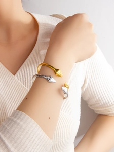 Close-up of gold and silver snake bracelets showing scale texture on a model's wrist