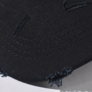 Close-up of distressed denim baseball cap with metal rings and frayed hole details