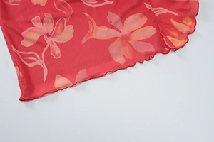 Détail de l'imprimé floral rouge sur tulle transparent avec des bords ondulés