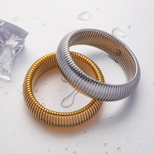 Elegante goldene und silberne elastische Tubogas-Schlangenarmbänder auf Wassertropfen