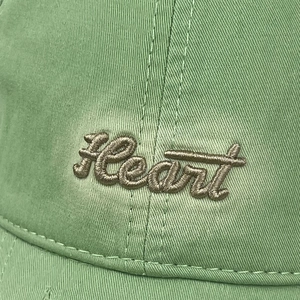Detailed view of grey 'Heart' embroidery on light green cotton twill baseball cap