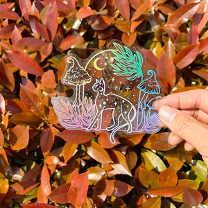 Detailed holographic cat and mushroom suncatcher sticker on natural autumn leaf background