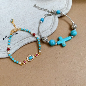 Detail of bohemian turquoise bracelets with pearl accents and a cross charm on leather