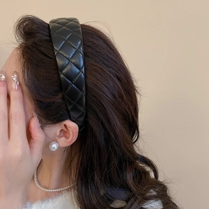 Detail of black quilted faux leather headband worn with elegant pearl accessories