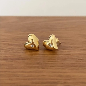 Macro shot of gold-plated heart stud earrings with sparkling white cubic zirconia center