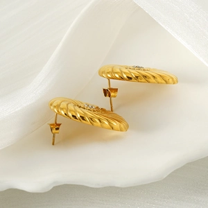 Vintage gold floral earrings with spiral texture and crystal stud on silk background