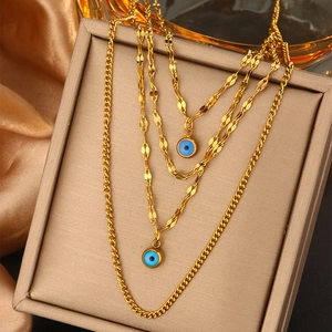 Detail of layered gold necklaces with turquoise evil eye pendants on jewelry padding