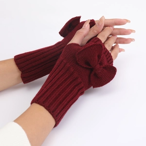 Close-up of deep red knitted fingerless gloves with a decorative bow detail