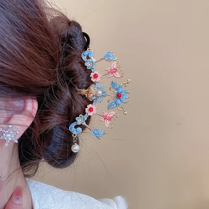 Détail d'un pic à cheveux fleur papillon en émail avec perle sur une coiffure élégante