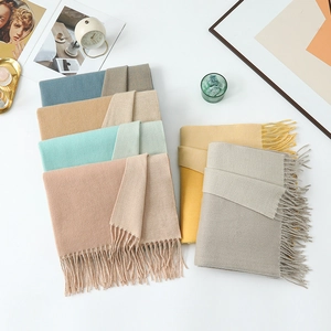 Close-up of soft cashmere-feel scarves with tassels in blue, beige, and mint green tones