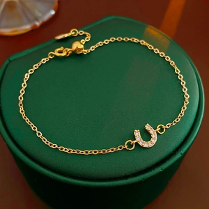 Bracelet doré avec pendentif fer à cheval en zircon sur boîte à bijoux verte