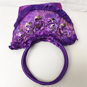 Detail of purple silk shoulder bag featuring 3D handmade roses and ruffled lace textures