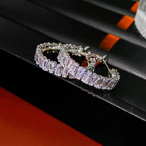 Macro shot of silver hoop earrings with baguette cut cubic zirconia in black texture