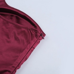 Detailed macro view of the invisible zipper and fine stitching on a wine red satin dress