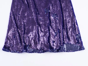 Dettaglio delle paillettes viola scintillanti su un abito da sera elegante con schiena scoperta