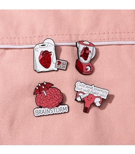 Makroaufnahme von 4 lustigen medizinischen Emaille-Pins mit Herz- und Hirndesign auf Jeans