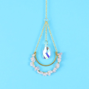 Macro shot of gold suncatcher with pink raw crystals and faceted teardrop prism pendant