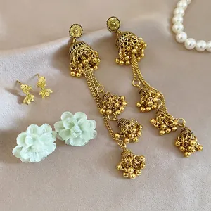Set of 3 pairs of vintage earrings featuring gold bells, fish studs, and green flowers