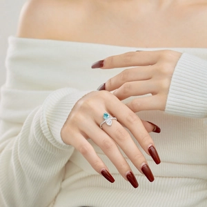 Elegant silver ring with light blue and white heart stones shown on a finger