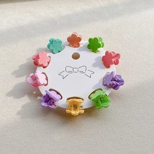 Macro view of 10-piece mini flower hair claws in colorful macaron shades on card display