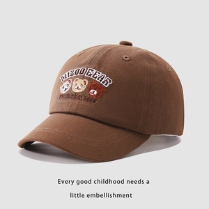 Dettaglio del cappellino bimbo in cotone marrone con orsetto ricamato e testo