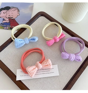 Set of four elastic bow hair ties in macaron colors displayed in a wooden tray