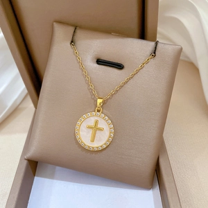 Detailed close-up of a gold cross pendant with crystal accents and mother of pearl inlay