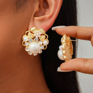 Detail of vintage gold flower earring with large pearl and sparkling rhinestones