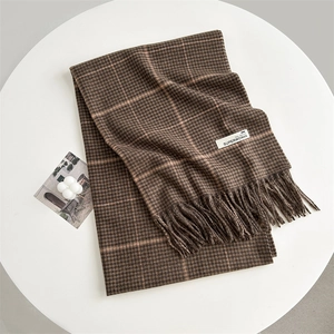 Detail of brown houndstooth scarf with pink stripes, tassels and woven fashion label