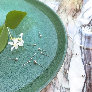 Classic 925 silver ball stud earrings scattered on a green plate and marble surface