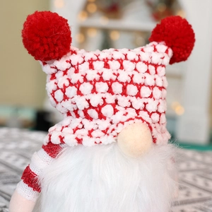 Detailed view of a red and white knitted Christmas gnome with a soft white beard and hat
