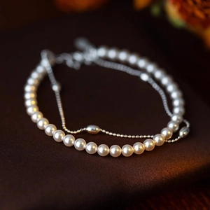 Dettaglio del bracciale a doppio strato con perle bianche e catena d'argento lucida