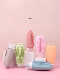 Close-up of 100ml silicone travel bottles with built-in scalp massage brush in pastel colors