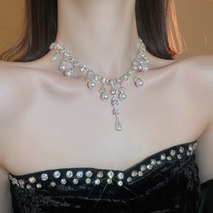 Detailed view of luxury teardrop zircon and pearl necklace draped on model's neck