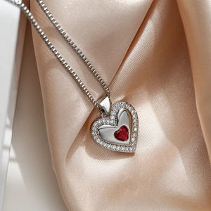 Double heart pendant necklace with red gemstone and white zircon on champagne silk fabric