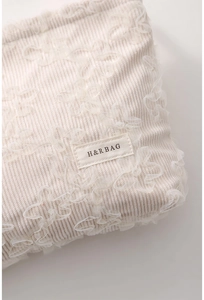 Detailed texture of beige corduroy pouch with floral lace 3D embroidery and brand label