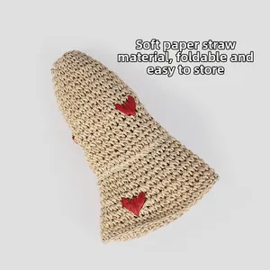 Detailed view of foldable beige straw hat showing soft fabric and red heart patterns