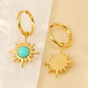 Golden sunburst hoop earrings featuring turquoise center stones on elegant silk fabric