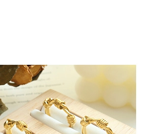 Detailed view of three gold-plated knot rings with pearls on a wooden display stand