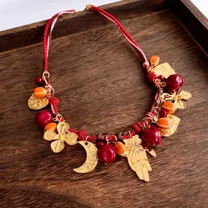 Collana etnica di perline con ciondoli dorati e perle di resina su vassoio legno