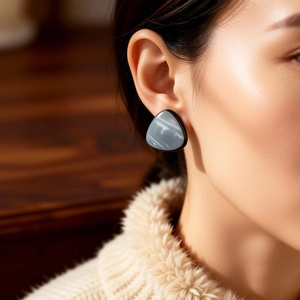 Macro shot of vintage resin triangle earrings with grey marble texture on a female model