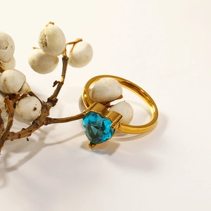 Detail of a 18k gold heart-shaped blue zircon ring set on an elegant white branch
