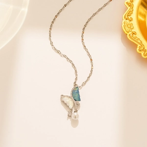Detail of butterfly pendant with iridescent wings and round pearl on thin gold chain